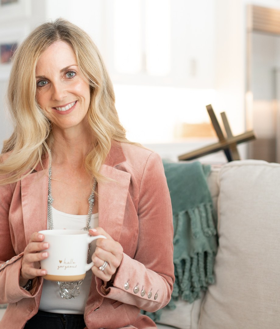 Lynda McDonell, founder of Pique Prosperity, smiling and holding a coffee mug